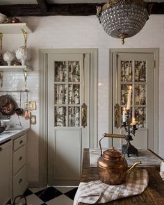 an old fashioned tea kettle is on the kitchen counter in front of two glass doors