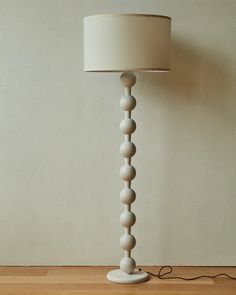 a white lamp on a wooden floor next to a wall