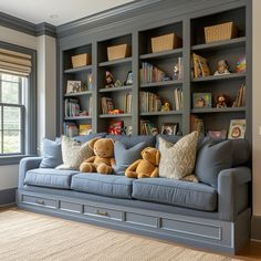 two stuffed animals are sitting on the couch in front of bookshelves and windows