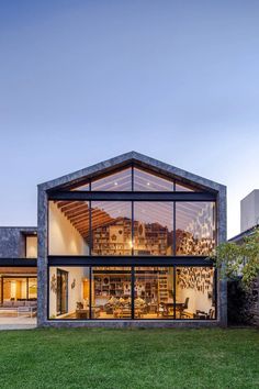 a modern house with glass walls and lots of windows on the outside, in front of grass