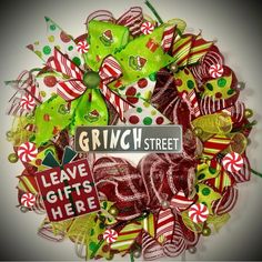 a christmas wreath made out of candy canes and ribbons with the words give gifts here on it