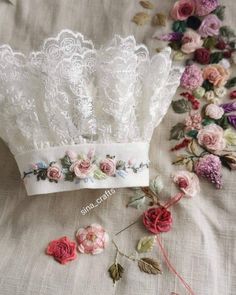 white lace headbands with pink flowers and greenery on the side, sitting on a bed