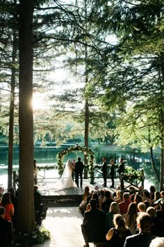 a wedding ceremony in the woods with sun shining down on the bride and groom standing at the alter