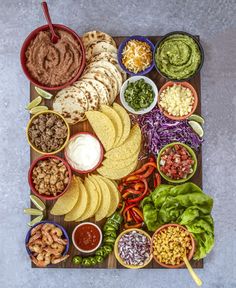 a platter filled with tacos, tortilla shells and salsa dips