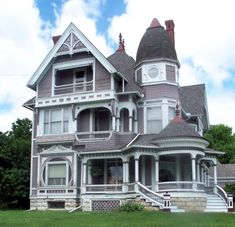 an old victorian style house in the middle of a grassy area with stairs leading up to it