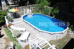 an aerial view of a swimming pool with deck chairs and umbrella in the backyard area