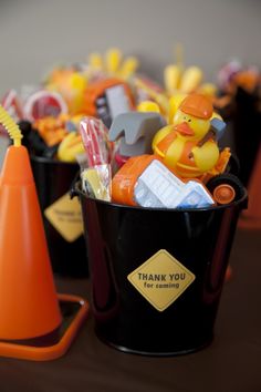 there are many small plastic toys in the buckets on the table with orange cones