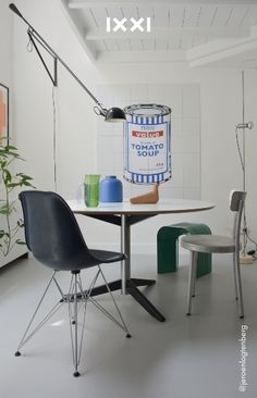 a table with two chairs and a painting on the wall in an empty room next to a chair