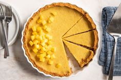 a pie sitting on top of a white plate next to a knife and fork,