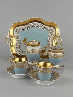 an ornately decorated tea set with gold trimmings and blue dishes on it