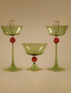 three green goblets sitting next to each other on top of a white table