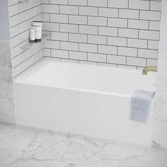 a white bath tub sitting next to a tiled wall