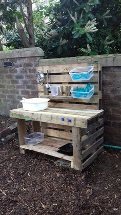 a sink made out of wooden pallets in the yard with two baskets on top