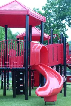 a red playground structure with a slide in the grass