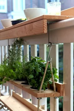 some plants are hanging on the side of a wooden shelf with rope attached to it