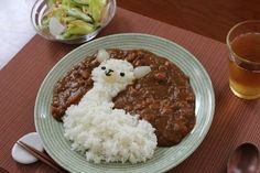 a plate topped with rice and meat next to a bowl of salad on a table