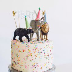 an elephant and lion figurines on top of a birthday cake with sprinkles