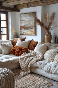 a living room filled with lots of pillows and blankets on top of a white couch