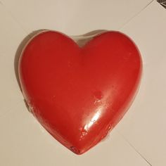 a red heart shaped object sitting on top of a white table next to a tile floor