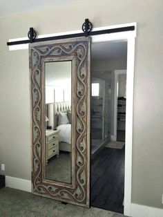 a large mirror sitting on the side of a wall next to a bed in a bedroom