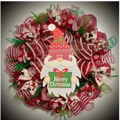 a christmas wreath with santa clause on it and green ribbon around the wreath is red, white and green