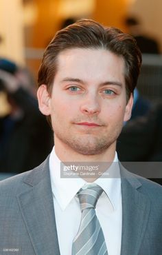 a man in a suit and tie poses for the camera on the red carpet at an event