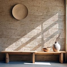 two vases are sitting on a wooden bench in front of a brick wall and window