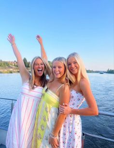 three women standing on a boat with their arms in the air