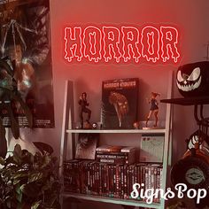 there is a book shelf with many books on it and a neon sign that says horror