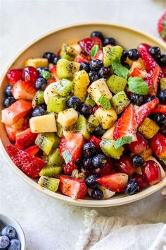 a fruit salad in a bowl with berries, kiwis, and blueberries