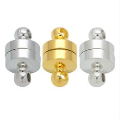 three gold and silver metal knobs on a white background