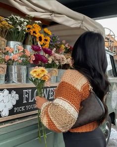 a woman standing in front of a truck with flowers on the side and a sign that says flower pick your