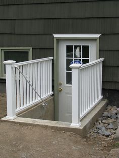 a small white door is open on the side of a house with rocks in front of it