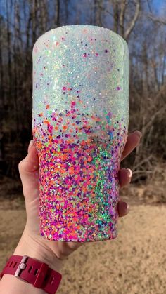 a person holding up a cup with colorful sprinkles on the outside and inside