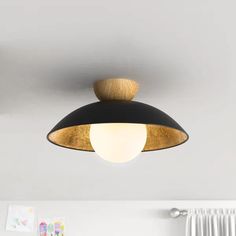 a black and gold ceiling light hanging from the ceiling in a room with white walls