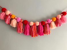 a pink, red and yellow tasselled garland with pom - poms