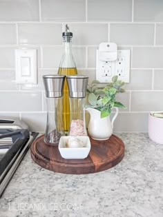 a kitchen counter with a bottle of olive oil and two cups on top of it