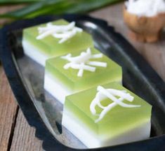 three pieces of food sitting on top of a black tray next to some green leaves