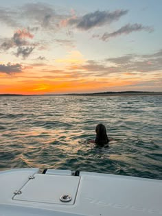 a woman swimming in the ocean at sunset