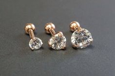 three pairs of diamond studs on a black surface with one earring in the middle