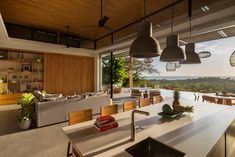 an open kitchen and living room area with large windows looking out onto the ocean at sunset