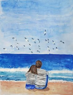 two people are sitting on the beach looking out at the water and birds flying overhead