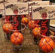 some oranges are sitting in small cups on a counter top with signs attached to them