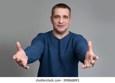 a man in a blue sweater is holding his hands out and making two thumbs up