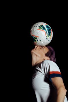 a woman with her head in the air and a soccer ball on top of her head