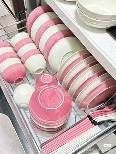 pink dishes and plates are stacked in the dishwasher drawer, which is open