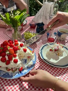 two people sitting at a table with a cake and flowers in the vase on it