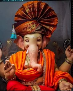 an elephant statue is dressed in orange and gold with a turban on it's head