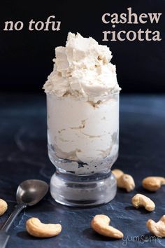 cashew ricotta in a small glass with spoons on the side and nuts scattered around