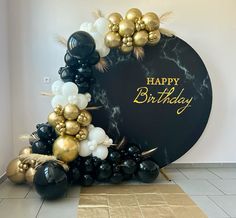 a black and gold balloon arch with happy birthday written on the front surrounded by balloons